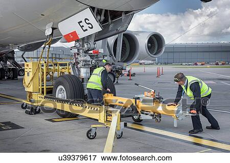Stock Photo - Ground crew fixing tow bar onto A380 aircraft at airport. Fotosearch