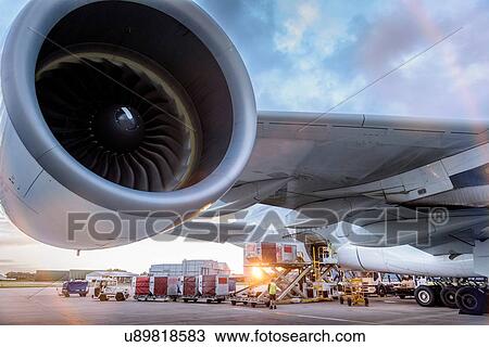 Stock Image - Ground crew loading A380 aircraft at sunset. Fotosearch
