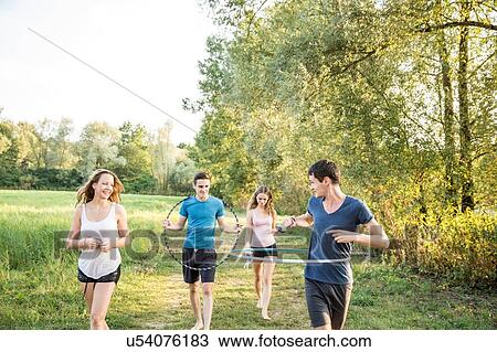 Stock Image - Group of friends in field, using hula hoops. Fotosearch