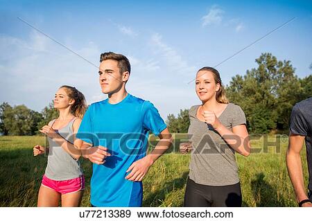Stock Photo - Group of friends running through field. Fotosearch