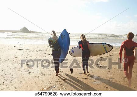 Group of surfers heading towards sea, carrying surfboards, rear view View Large Photo Image Stock Photo - Group of surfers heading towards sea, carrying surfboards, rear view. Fotosearch