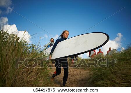 Group of surfers heading towards sea, carrying surfboards View Large Photo Image Stock Photograph - Group of surfers heading towards sea, carrying surfboards. Fotosearch
