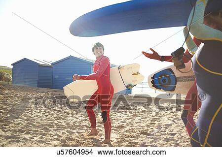 Picture - Group of surfers on beach, carrying surfboards. Fotosearch