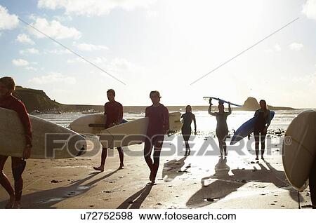 Group of surfers, walking on beach, carrying surfboards View Large Photo Image Stock Photo - Group of surfers, walking on beach, carrying surfboards. Fotosearch