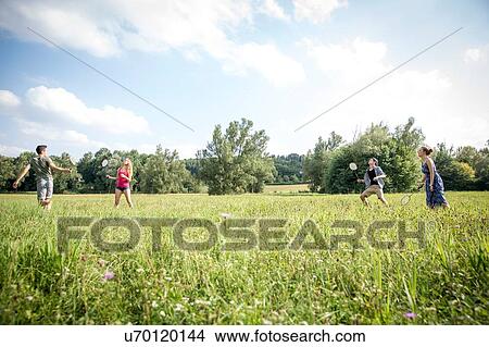 Picture - Group of young adults playing badminton in field. Fotosearch