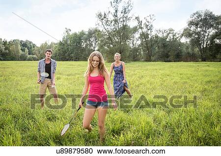 Group of young adults playing badminton in field View Large Photo Image Stock Image - Group of young adults playing badminton in field. Fotosearch