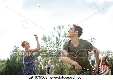 Group of young adults playing badminton in field View Large Photo Image Stock Photo - Group of young adults playing badminton in field. Fotosearch