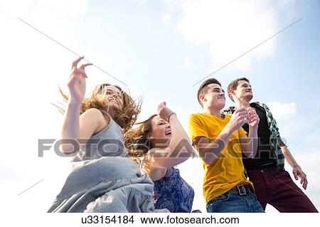 Group of young adults, running, outdoors, low angle view View Large Photo Image Picture - Group of young adults, running, outdoors, low angle view. Fotosearch