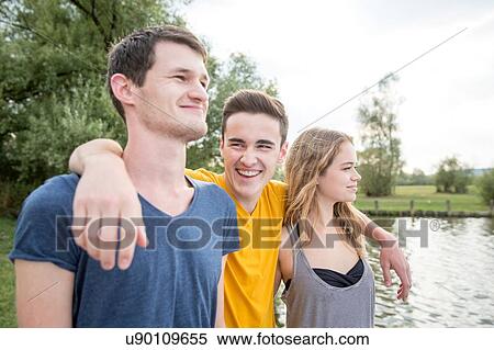 Group of young adults, standing by lake, smiling View Large Photo Image Stock Photography - Group of young adults, standing by lake, smiling. Fotosearch