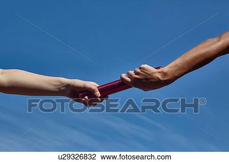 Hands of female relay runners passing baton against blue sky View Large Photo Image Stock Image - Hands of female relay runners passing baton against blue sky. Fotosearch