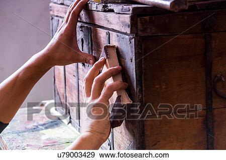 Stock Photo - Hands of man sanding wooden trunk suitcase. Fotosearch