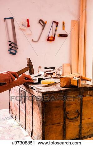 Stock Image - Hands of person hammering trunk suitcase. Fotosearch