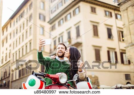 Happy young couple on moped posing for smartphone selfie, Florence, Italy View Large Photo Image Stock Photo - Happy young couple on moped posing for smartphone selfie, Florence, Italy. Fotosearch