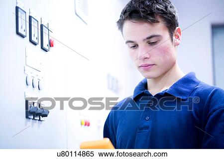 Stock Photography - Head and shoulders of young man in switchgear control room looking down. Fotosearch