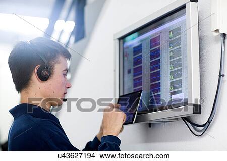 Low angle side view of young man wearing headset using digital tablet View Large Photo Image Picture - Low angle side view of young man wearing headset using digital tablet. Fotosearch