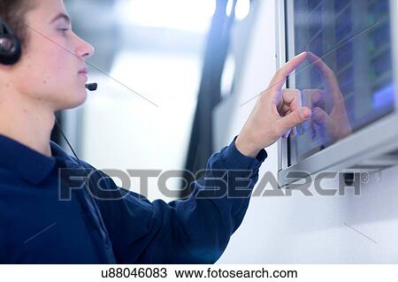 Low angle side view of young man wearing headset using touch screen computer monitor View Large Photo Image Stock Image - Low angle side view of young man wearing headset using touch screen computer monitor. Fotosearch