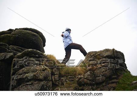 Low angle view of woman on rock formation, Dartmoor, Devon, UK View Large Photo Image Stock Photograph - Low angle view of woman on rock formation, Dartmoor, Devon, UK. Fotosearch