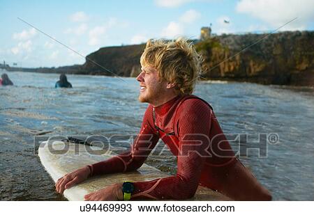 Male surfer in sea, holding surfboard, resting View Large Photo Image Stock Image - Male surfer in sea, holding surfboard, resting. Fotosearch