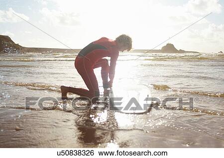 Male surfer untying surfboard from ankle View Large Photo Image Stock Photograph - Male surfer untying surfboard from ankle. Fotosearch