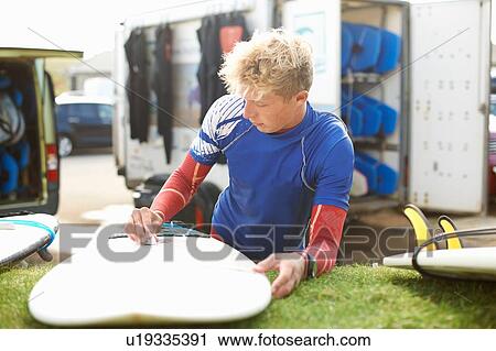 Male surfer waxing surfboard View Large Photo Image Stock Image - Male surfer waxing surfboard. Fotosearch