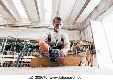 Stock Photograph - Man sanding skateboard in workshop. Fotosearch