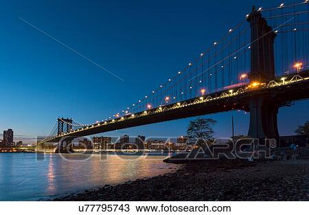 Stock Image - Manhattan bridge from riverbank at night, New York, USA. Fotosearch