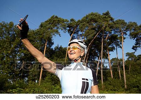 Mature cyclist taking selfie beside forest View Large Photo Image Stock Image - Mature cyclist taking selfie beside forest. Fotosearch