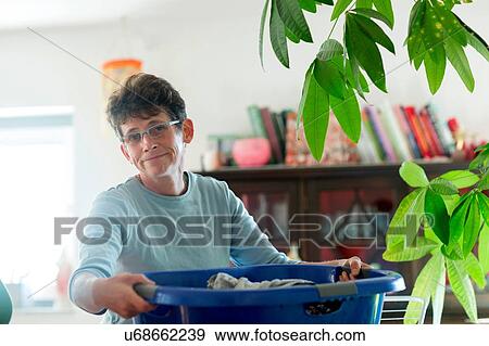 Mature woman carrying laundry basket looking at camera View Large Photo Image Stock Photo - Mature woman carrying laundry basket looking at camera. Fotosearch