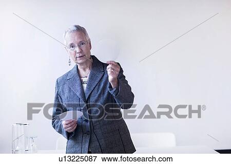 Mature woman giving lecture holding up white circle looking at camera View Large Photo Image Stock Photo - Mature woman giving lecture holding up white circle looking at camera. Fotosearch