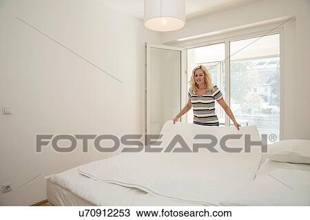 Mature woman in bedroom holding blanket making bed View Large Photo Image Stock Image - Mature woman in bedroom holding blanket making bed. Fotosearch