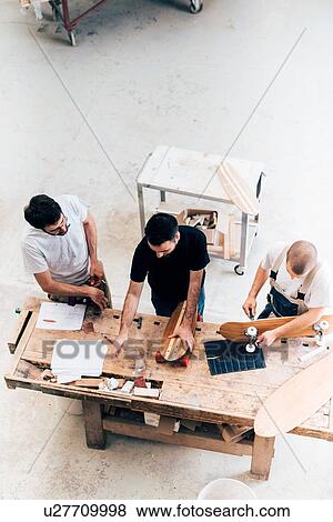 Stock Photo - Men working on skateboards in workshop. Fotosearch