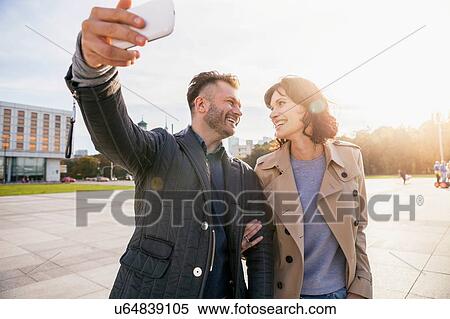 Mid adult couple taking selfie on phone View Large Photo Image Stock Photography - Mid adult couple taking selfie on phone. Fotosearch