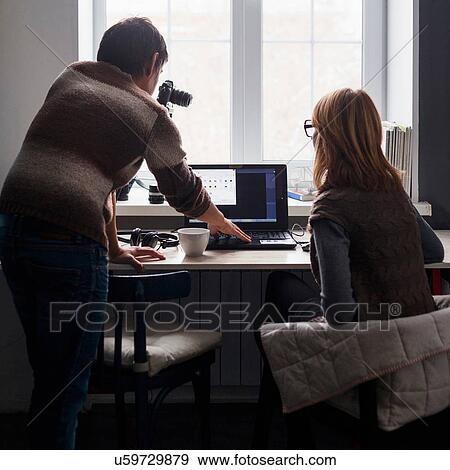 Mid adult man and woman using laptop at desk, rear view View Large Photo Image Stock Photo - Mid adult man and woman using laptop at desk, rear view. Fotosearch