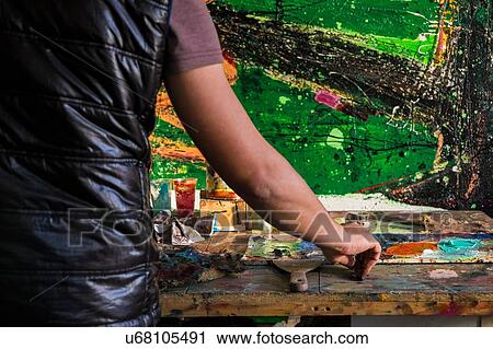 Stock Image - Mid adult man, painting, mid section, rear view. Fotosearch