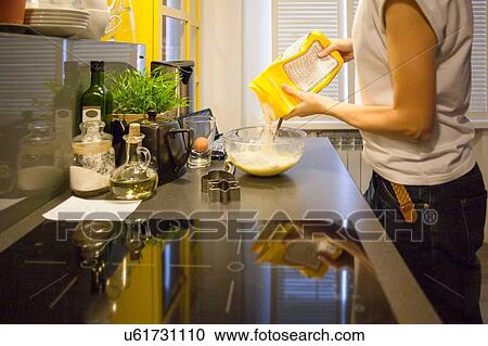 Mid adult woman pouring flour into mixing bowl at kitchen counter View Large Photo Image Stock Image - Mid adult woman pouring flour into mixing bowl at kitchen counter. Fotosearch