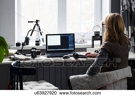 Mid adult woman sitting at desk, using computer, rear view View Large Photo Image Stock Image - Mid adult woman sitting at desk, using computer, rear view. Fotosearch