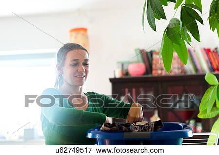 Stock Photo - Mid adult woman sorting clothing laundry basket, looking down. Fotosearch