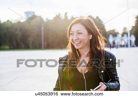Stock Photograph - Mid adult woman wearing earphones. Fotosearch