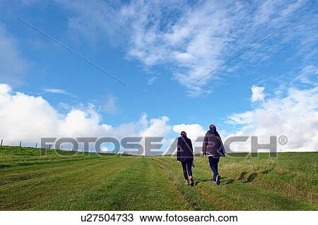 Stock Image - Mother and daughter walking in field, rear view, South Downs, East Sussex, UK. Fotosearch