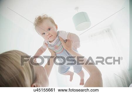 Stock Image - Mother holding baby daughter in air. Fotosearch