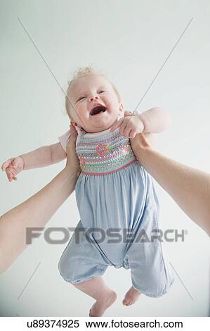 Stock Photography - Mother holding baby daughter in air. Fotosearch