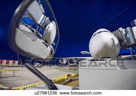 Stock Photograph - Night over A380 aircraft on stand at airport, reflected in wing mirror of ground crew vehicle. Fotosearch