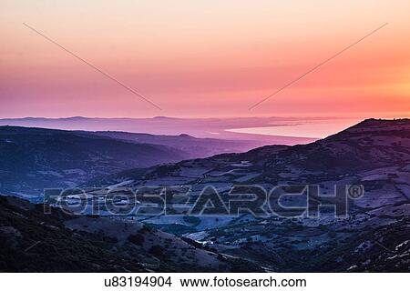 Picture - Orange sunset over ocean and rugged mountain farmland, Castelsardo, Sardinia, Italy. Fotosearch