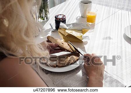 Over shoulder view of mature woman spreading butter onto bread View Large Photo Image Stock Photograph - Over shoulder view of mature woman spreading butter onto bread. Fotosearch