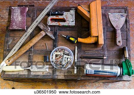 Stock Image - Overhead view of hand tools on wooden trunk suitcase. Fotosearch