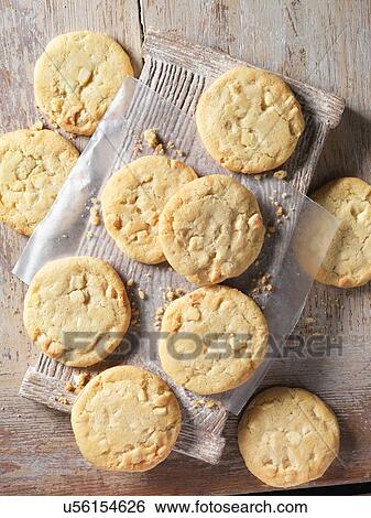Stock Photograph - Overhead view of white chocolate chunk cookies on wood. Fotosearch