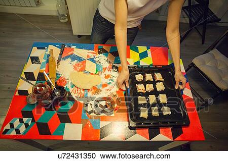 Overhead view of woman lifting baking tray from kitchen table View Large Photo Image Stock Image - Overhead view of woman lifting baking tray from kitchen table. Fotosearch