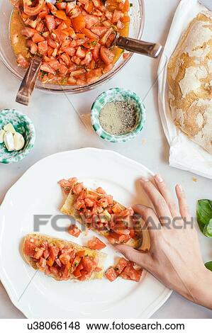 Overhead view of womans hand picking Italian tomato bruschetta from plate View Large Photo Image Stock Photo - Overhead view of womans hand picking Italian tomato bruschetta from plate. Fotosearch