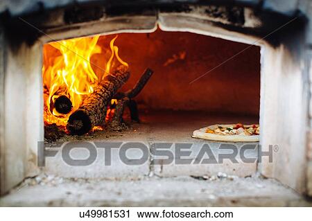Stock Image - Pizza in traditional pizza wood oven. Fotosearch