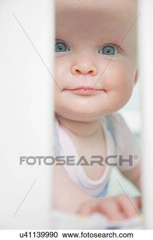 Portrait of baby girl looking through bars on cot View Large Photo Image Stock Image - Portrait of baby girl looking through bars on cot. Fotosearch